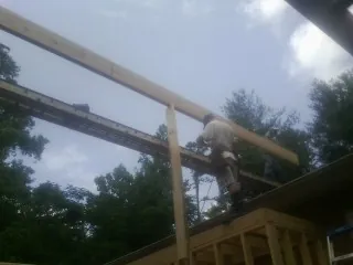 Carpenter setting a ridge beam over a new addition frame — Ice Dam Removal by Roofing Brothers in Colonial Heights