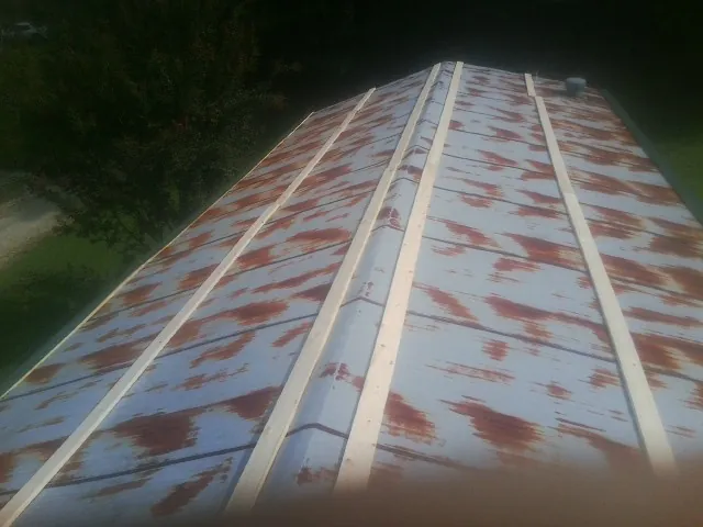 Rusted metal roof panels with new wood purlins before replacement — Storm Damage Roof Repair in Colonial Heights by Roofing Brothers