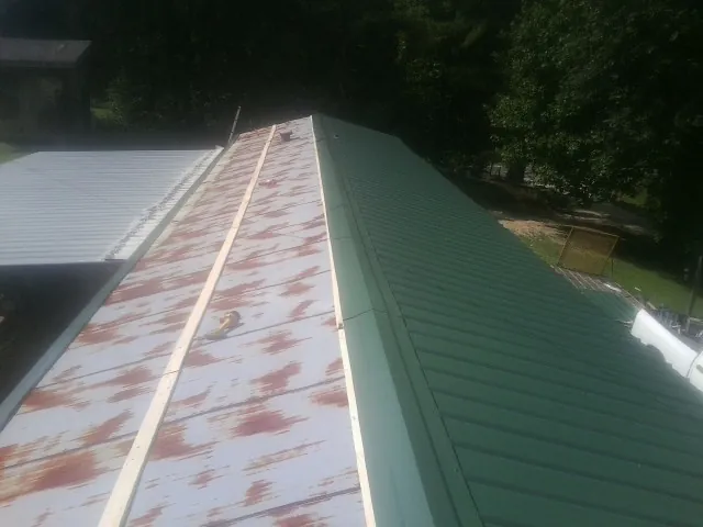 Old rusted panels beside newly installed green metal roofing — Wind Damage Roof Repair by Roofing Brothers in Colonial Heights