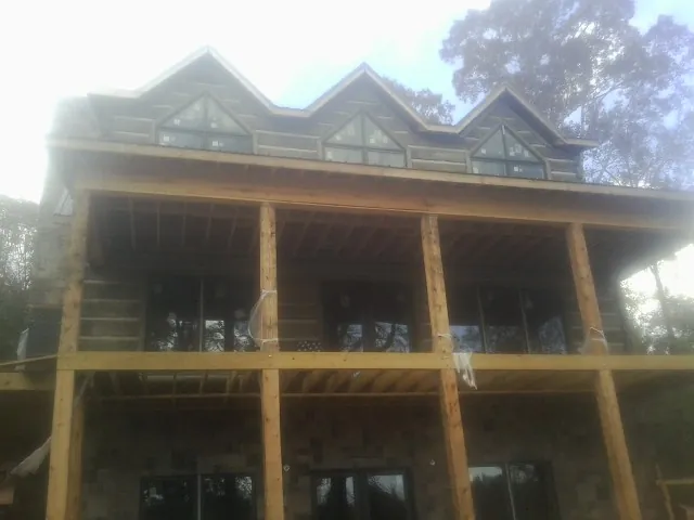 Dormers and porch framing on a large log home under construction — Roof Coating work by our crew in Colonial Heights