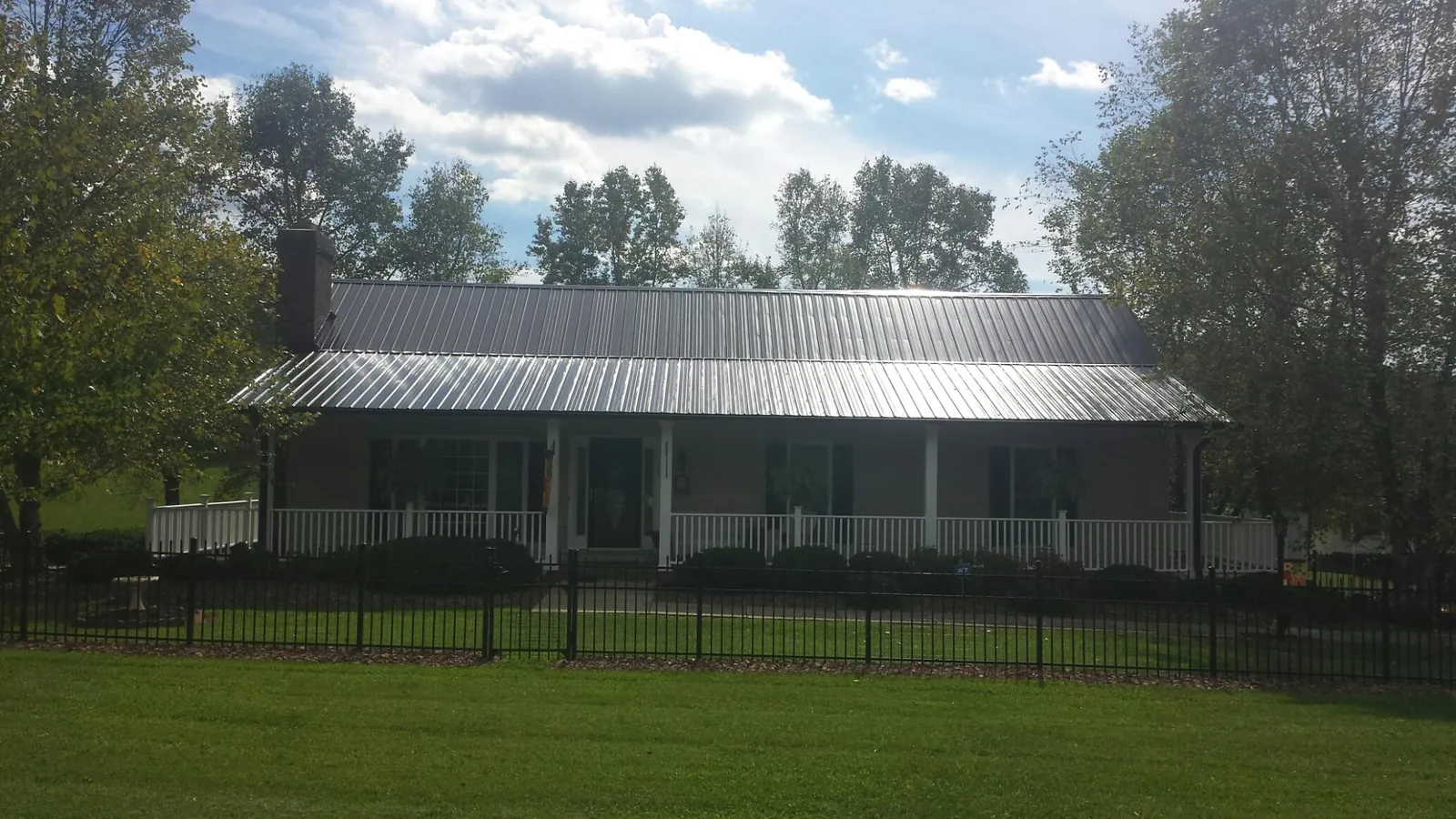 Gray metal roof on a brick ranch with a full width front porch — Gutter Guard Installation work by our crew in Colonial Heights