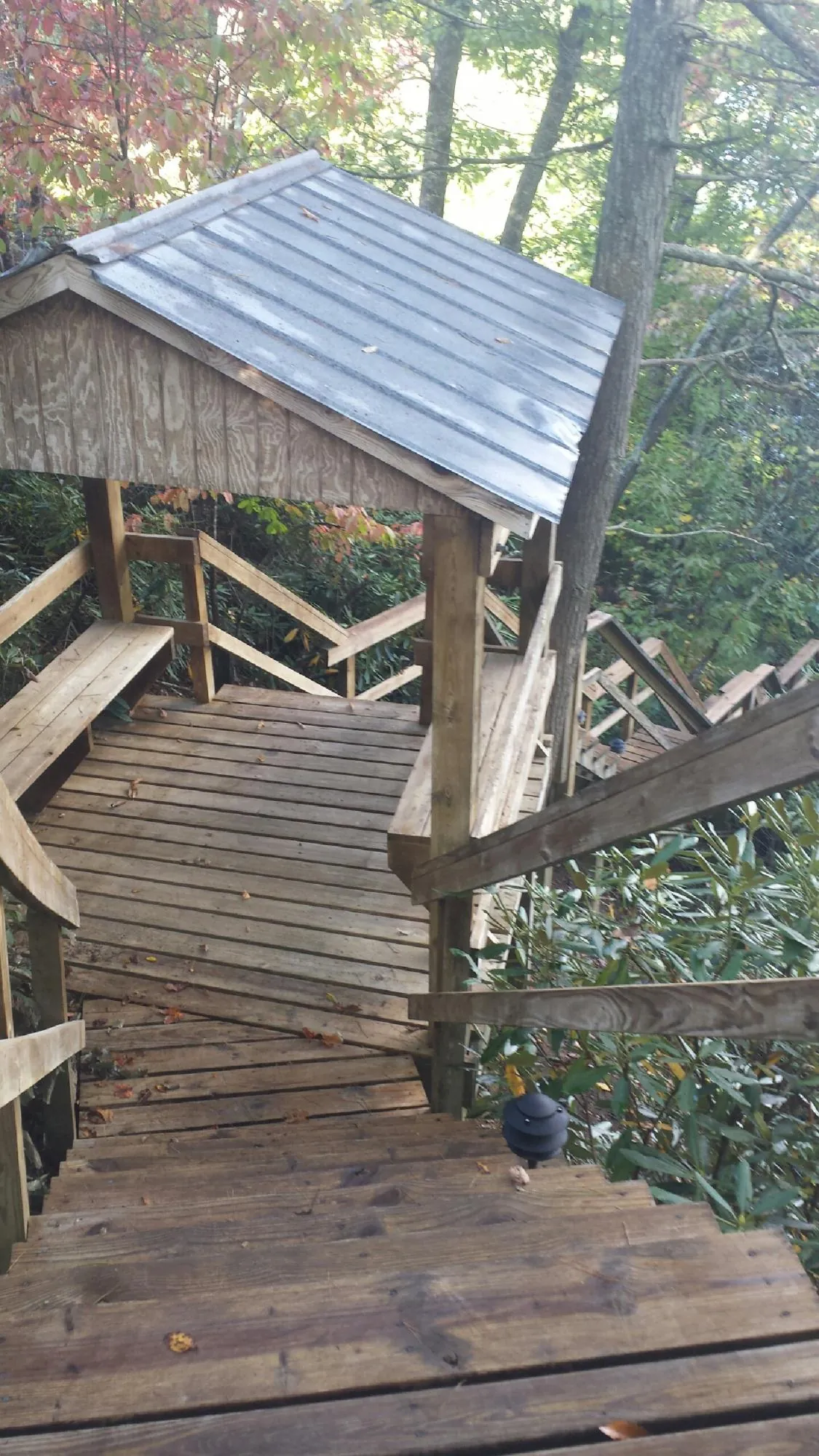 Metal roofed shelter over wooden steps on a wooded walkway — Skylight Repair & Installation work by our crew in Colonial Heights