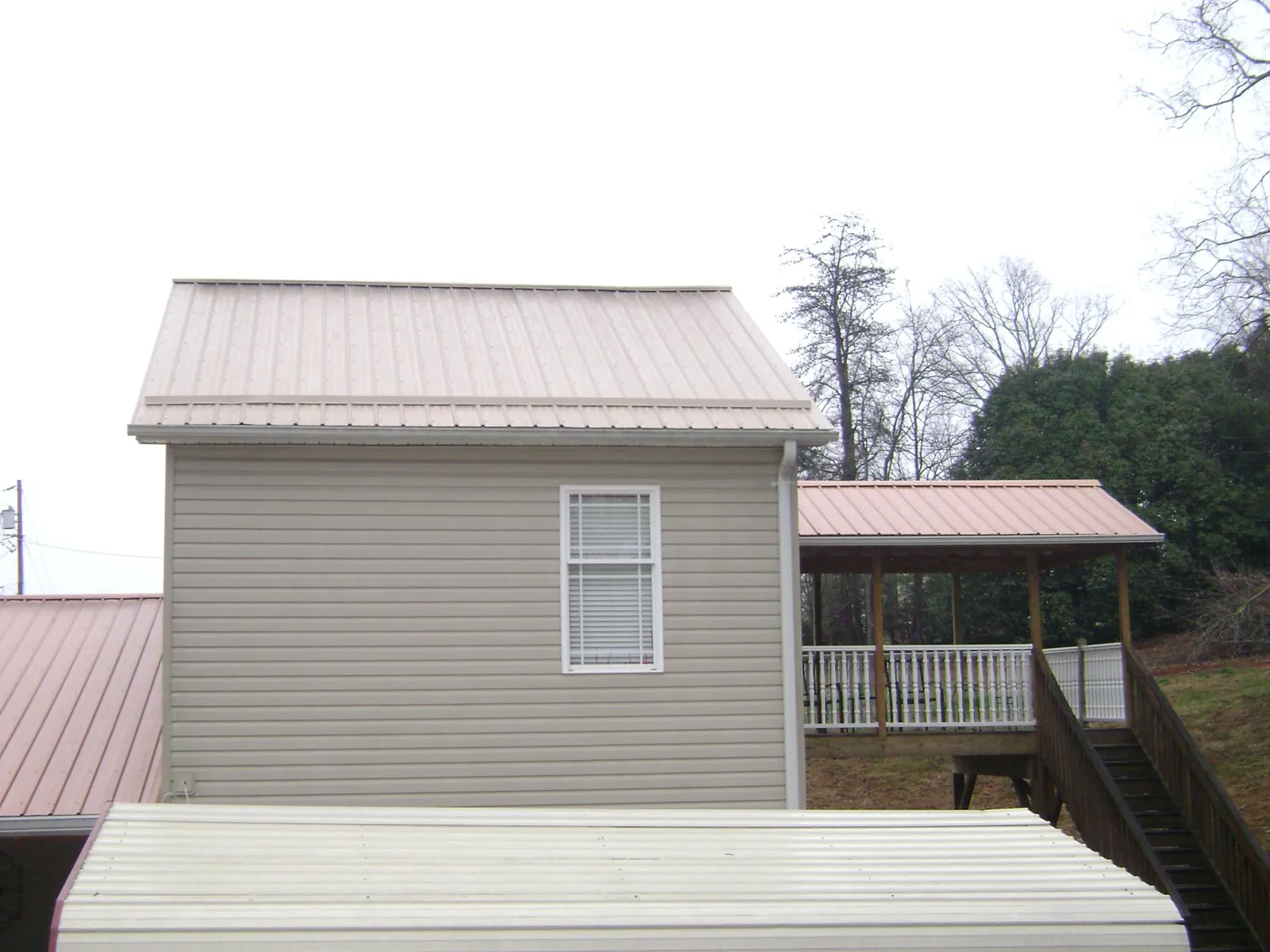 Tan metal roofs on a two story addition and attached porch, from a Roof Replacement job in Colonial Heights
