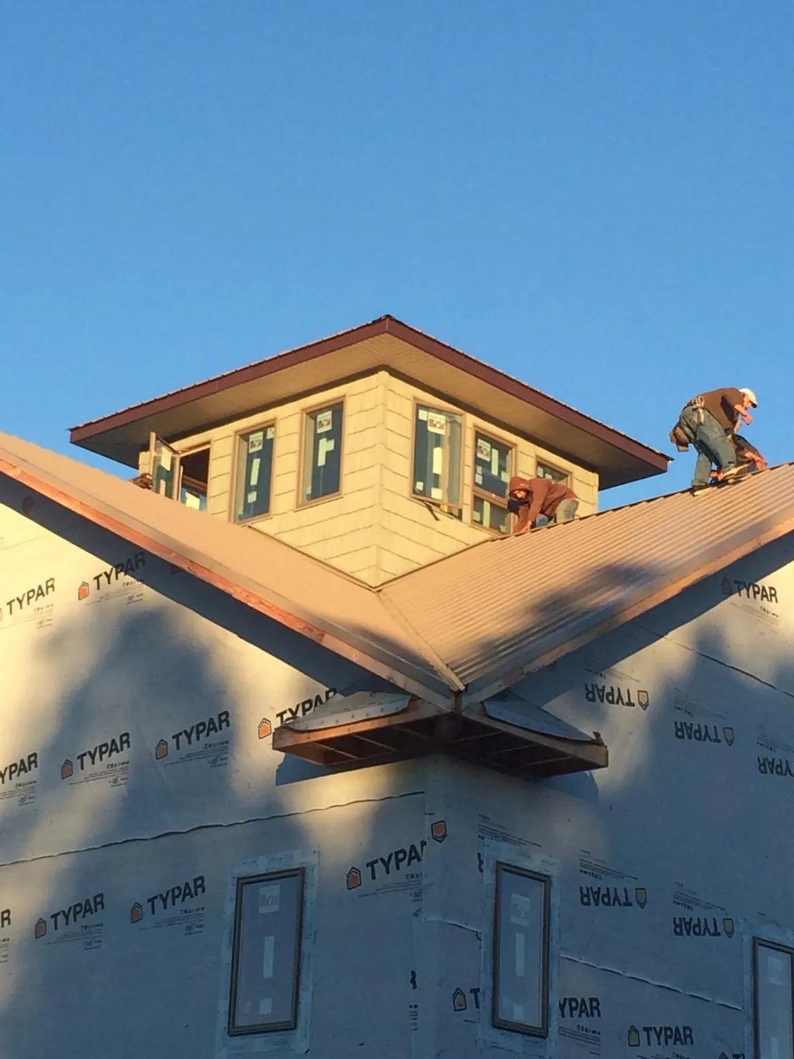 Roofers working around a rooftop cupola on a new metal roof at sunset — Roof Waterproofing in Colonial Heights by Roofing Brothers